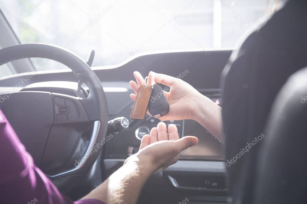 Close-up of a hand giving car keys to a driver inside the car