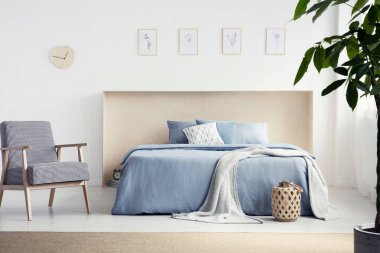 Desenli koltuk mavi yatak doğal yatak odası iç posterler ile battaniye ile yanındaki. Gerçek fotoğraf