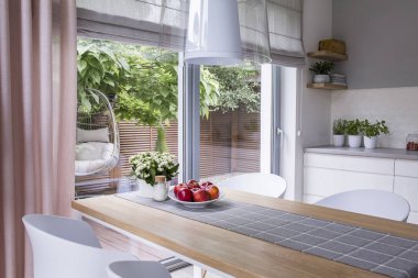 Bir modern yemek odası iç tablo, tabak elma ve görünümü üzerinde bir salıncak bir teras ile gerçek fotoğraf