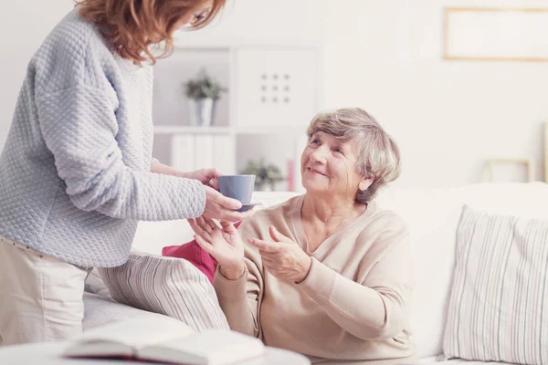 Caregiver Giving Cup Tea Smiling Relaxed Elderly Woman — Stock Photo, Image