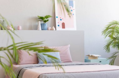 Gerçek fotoğraf parlak yatak odası iç dekora, pastel sayfaları, Komidin ve modern sanat resim kitap ile çift kişilik yatak