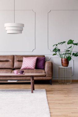 Masa lambası altında deri kanepe yastıkları parlak düz iç ile yanındaki masada bitki. Gerçek fotoğraf