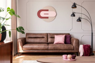 Modern oturma odası iç poster ve tablo ile deri koltukta yanındaki siyah lamba. Gerçek fotoğraf