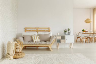 Bitkiler üzerinde beyaz battaniye sepet içinde düz iç ahşap kanepenin yanındaki dolap. Gerçek fotoğraf