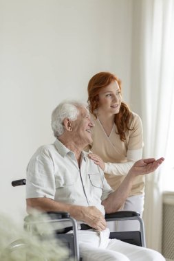 Hasta bir yaşlılık ev için bir hemşire konuşurken gülümseyen bir tekerlekli sandalyede