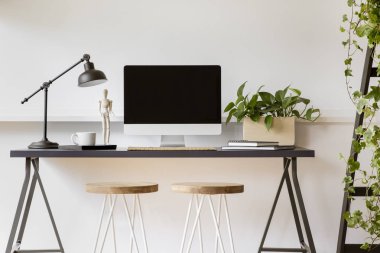 Masa lambası, masaüstü bilgisayar ve bitki beyaz çalışma alanı iç ahşap tabureler. Gerçek fotoğraf