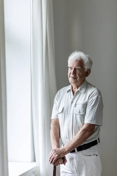 Ηλικιωμένους Man Εκμετάλλευση Επάνω Ένα Ζαχαροκάλαμο Και Στέκεται Ένα Δωμάτιο — Φωτογραφία Αρχείου