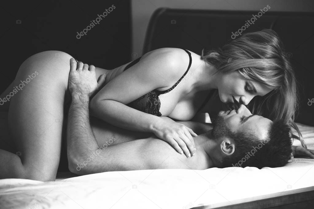 Man embracing and kissing beautiful woman during sensual foreplay in the bedroom