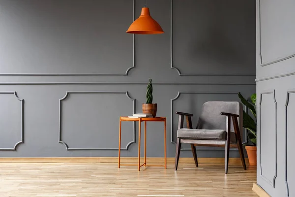 Oranje Lamp Boven Tafel Met Plant Naast Fauteuil Grijze Appartement — Stockfoto