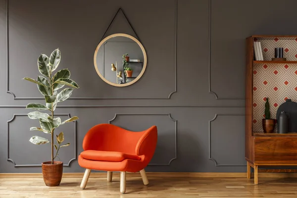 明亮的橙色扶手椅 一个复古的木制橱柜和一个灰色的墙壁上的镜子与塑造在一个时髦的客厅内部与复制空间的地方为一盏灯 真实照片 — 图库照片