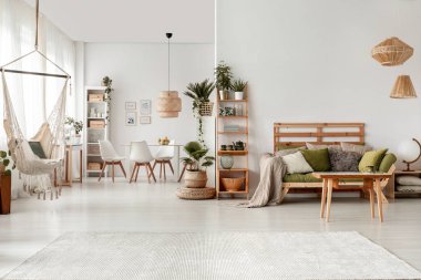 Ahşap masa hamak ve bitkiler ile beyaz düz iç yeşil kanepe önünde. Gerçek fotoğraf