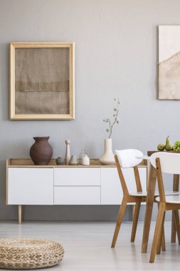 Kabarık beyaz dolap yukarıda posteri ile parlak yemek odası iç ahşap sandalye yanında. Gerçek fotoğraf