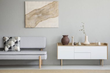 Gri desenli minder ayakta aydınlık oturma odası iç dekorasyonu ile beyaz dolap ve poster duvarda asılı kumaş ile gerçek fotoğraf kanepeyle