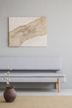 Gri oturma odası iç kanepe yukarıda posteri ile kahverengi halı üzerinde çiçekli vazo. Gerçek fotoğraf