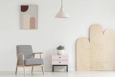 Desenli koltuk bitki poster ve lamba ile beyaz düz iç dolapla yanında. Gerçek fotoğraf