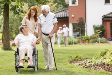Yaşlı bir çift ile onların bekçi Özel Rehabilitasyon Kliniği dışında bahçede devre dışı.
