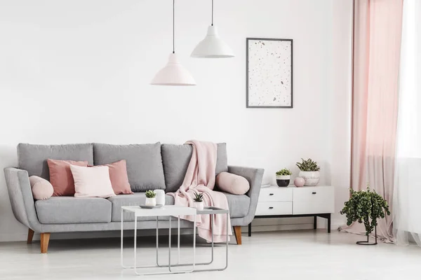 粉红色枕头在灰色沙发在白色公寓内部与海报和灯以上表 真实照片 — 图库照片