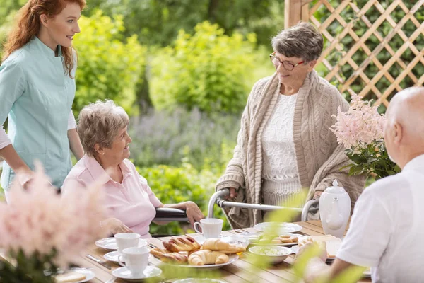 Grupo Pensionistas Con Cuidador Desayunando Junto Una Mesa Porche Fuera —  Fotos de Stock