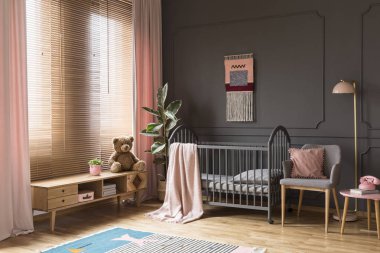 Peluş oyuncak çocuğun pastel yatak odası iç gri beşiği yanında ahşap dolap üzerinde. Gerçek fotoğraf