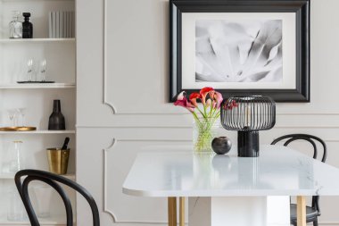 Siyah lamba ve beyaz zarif yemek odası iç poster ve sandalyeler ile masaya çiçek. Gerçek fotoğraf