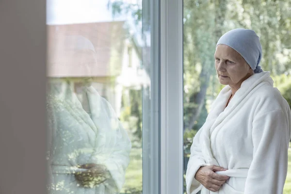 孤独的妇女与癌症站在窗口旁边 — 图库照片