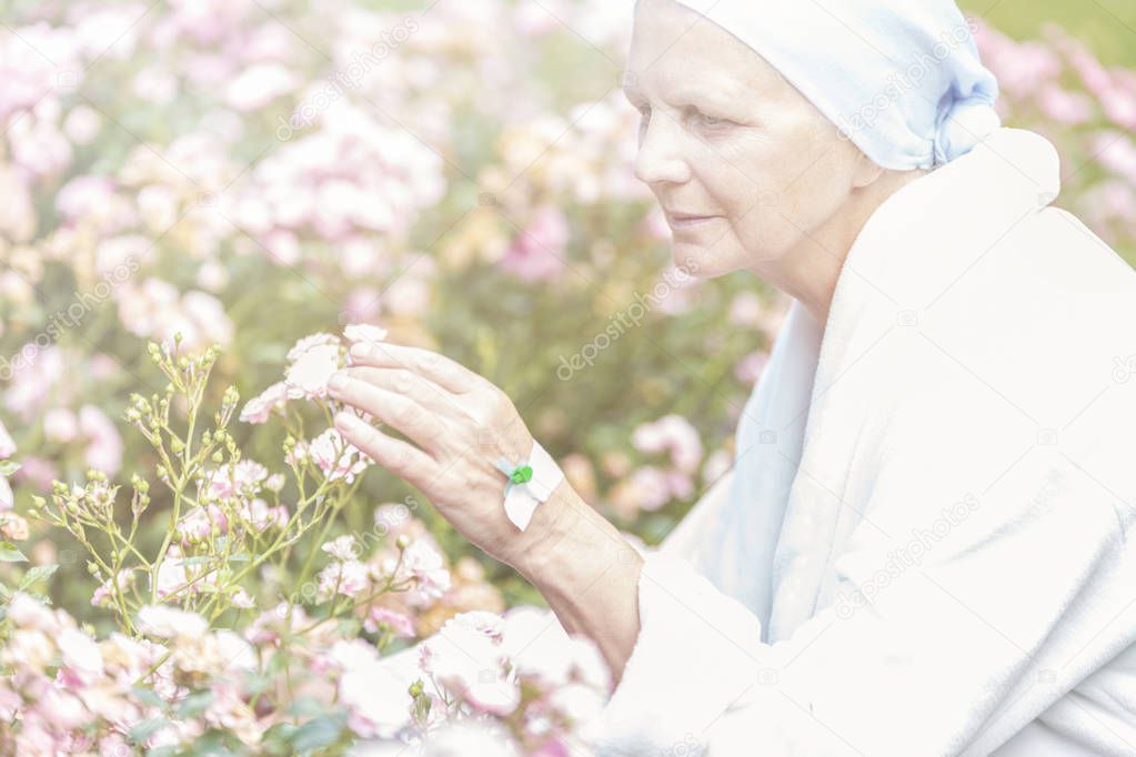 Senior with cancer enjoying flowers in a garden