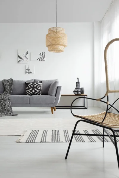 グレーのソファの上のパターンのブランケットと白の広々 としたアパートメント インテリア ランプ 実際の写真 — ストック写真