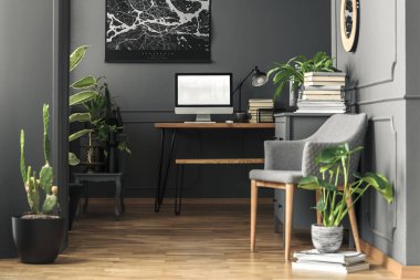 Ev ofis iç mockup bilgisayar masaüstü ile gri tekli yanında bitki. Gerçek fotoğraf