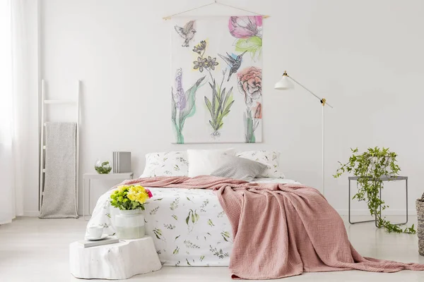 ベッドと明るい寝室のインテリアの黄色の新鮮な切り花の束は 白いリネンと桃の毛布に身を包んだ ベッドの上の壁のファブリック 実際の写真 — ストック写真