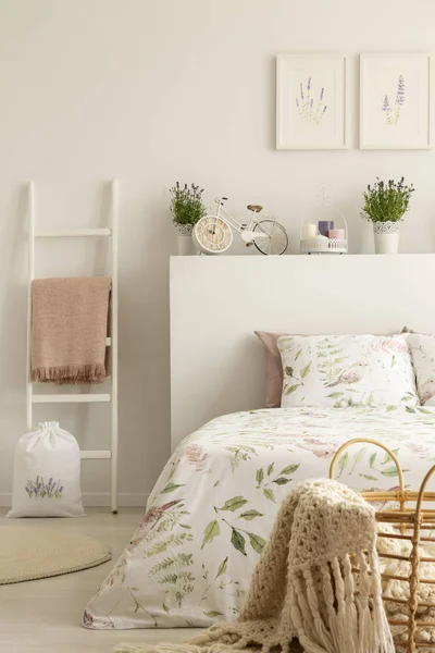 梯子与粉红色的毯子旁边的床在女性卧室内部与薰衣草花卉和海报 真实照片 — 图库照片