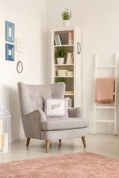 垫子上的灰色扶手椅在明亮的客厅内部与海报和粉红色的地毯 真实照片 — 图库照片