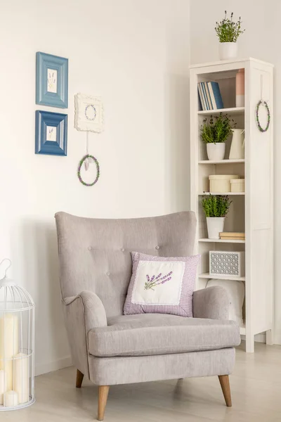 灰色扶手椅与枕头在明亮的客厅内部与海报和货架 真实照片 — 图库照片