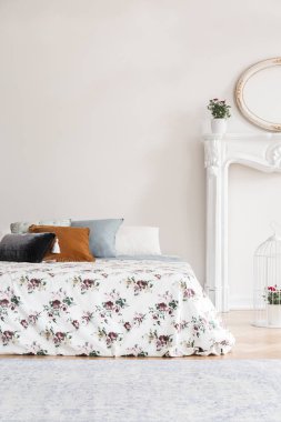 Kadınsı İngiliz tarzı yatak odası iç gül desen kapak ve bir boş kopya boşluk duvar karşı çok renkli yastıklar bir yatak ile. Gerçek fotoğraf.