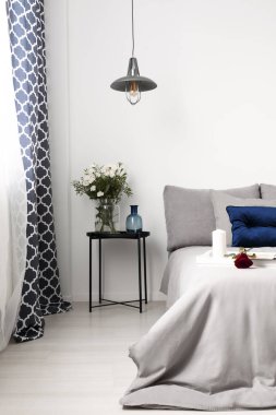 Gerçek fotoğraf gri yatak odası iç bir başucu tablonun bir yatak bir mum yakın ve gül