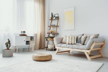 Kabarık aydınlık oturma odası iç poster ve kaktüs ile tahta kanepenin önünde. Gerçek fotoğraf