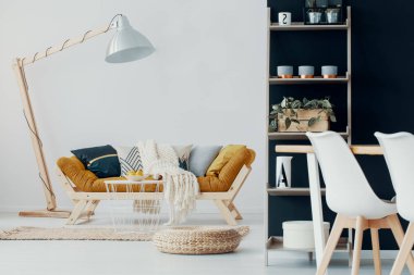 Ahşap lamba kabarık ve tablo ile modern beyaz düz iç hardal kanepe yanında. Gerçek fotoğraf