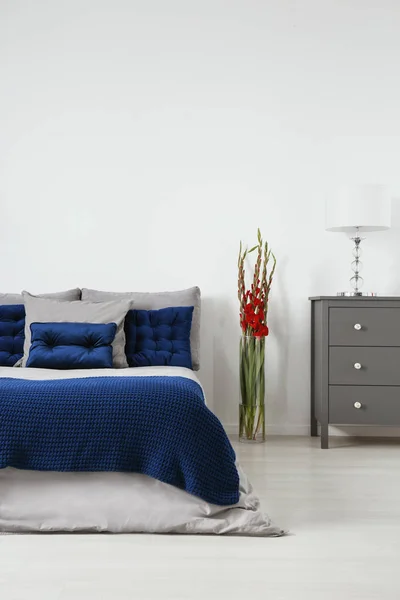 在一个最小风格的卧室内饰的床上 在深蓝色和有机棉亚麻布绗缝垫 空白的白色墙壁背景 真实照片 — 图库照片