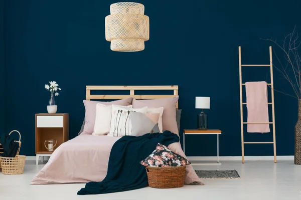 キングサイズのベッド つのベッドサイド テーブルと青い寝室のインテリア 毛布および枝編み細工品バスケットとはしごの本物の写真で多くのクッション — ストック写真
