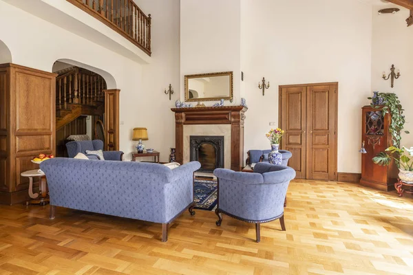 ソファと椅子が木製の家具と古典的な暖炉のあるエレガントなリビング ルーム インテリアでのブルーのセットの実際の写真 — ストック写真