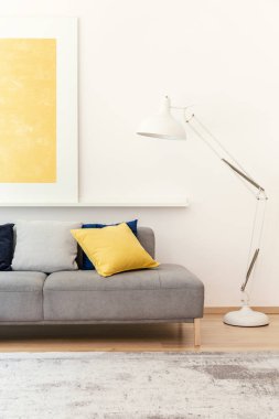 Modern oturma odası iç sarı poster ve halı gri kanepenin yanındaki beyaz lamba. Gerçek fotoğraf