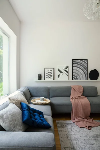 黒と白の芸術と本と居心地の良いソファの上の棚の上のポスターとリラックス 単色のリビング ルームのインテリアの枝編み細工品皿のマグカップ — ストック写真