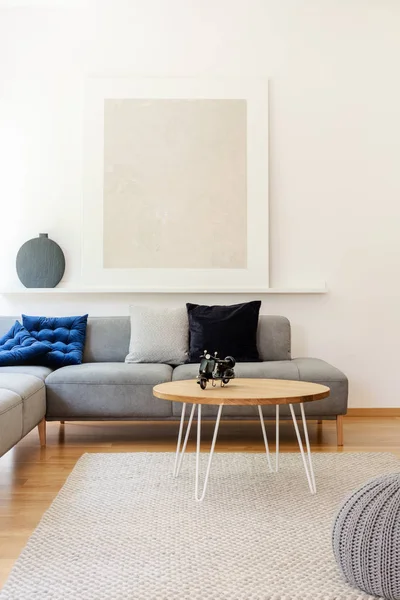 白い壁とシンプルなリビング ルームのインテリアに枕と灰色のコーナー ソファーの上の棚の上の灰色のポスター — ストック写真
