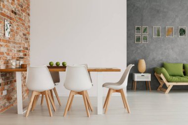 Modern çatı katı bir parlak ve doğal oturma odası iç ahşap yemek masası ve sandalyeler tarafından maruz bir tuğla duvar