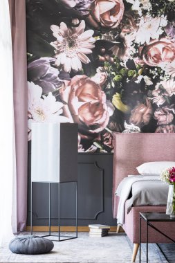 Kitap ve pembe desenli yatak odası iç çiçek duvar kağıdı ile yatakta yanındaki gri yastık. Gerçek fotoğraf