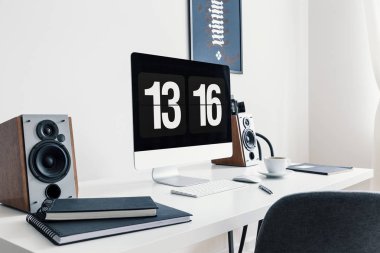 Sarmal bloknot, hoparlör ve beyaz duvarlı bir şık çalışma alanı iç modern bir masaüstü bilgisayar ile beyaz masa Close-up. Gerçek fotoğraf.