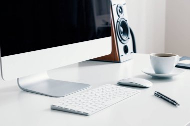 Cup of coffee, keyboard and desktop computer on desk in white home office interior. Real photo clipart