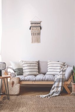 Battaniye ve minderler bej oturma odası iç kahverengi halı ile ahşap kanepede. Gerçek fotoğraf