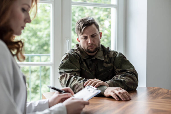Грустный солдат с депрессией и военным синдромом во время терапии у психиатра
