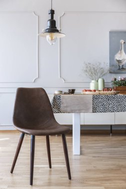 Kahverengi sandalye beyaz yemek odası iç tablo ile ve kalıplama ile duvar lambası altında. Gerçek fotoğraf