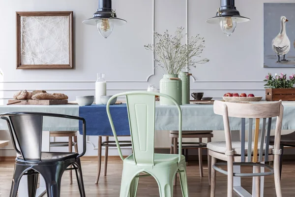 五颜六色的椅子在桌在小屋灰色饭厅室内用灯和海报 真实照片 — 图库照片